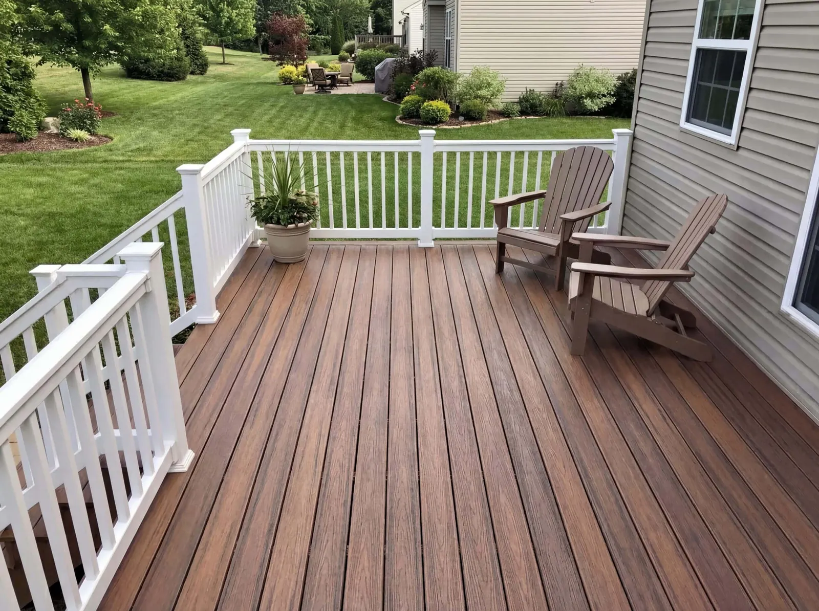Composite deck with white railings on the back of a vinyl-sided house