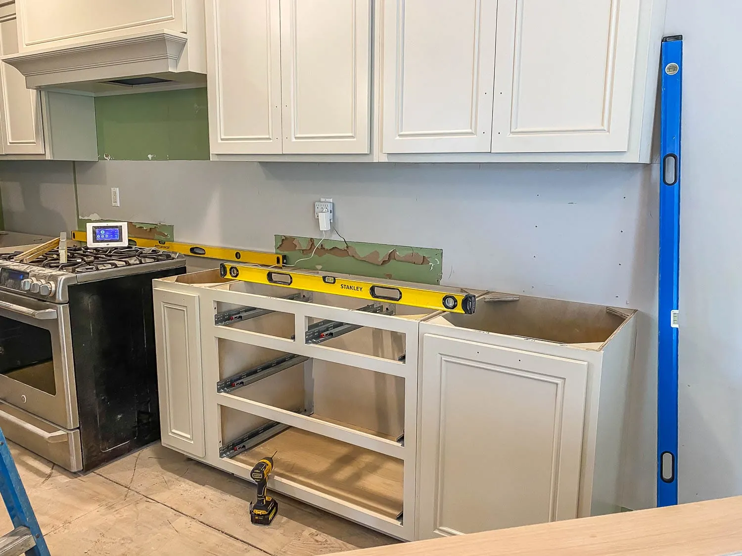 Base cabinets being set level with long levels during a kitchen cabinet installation