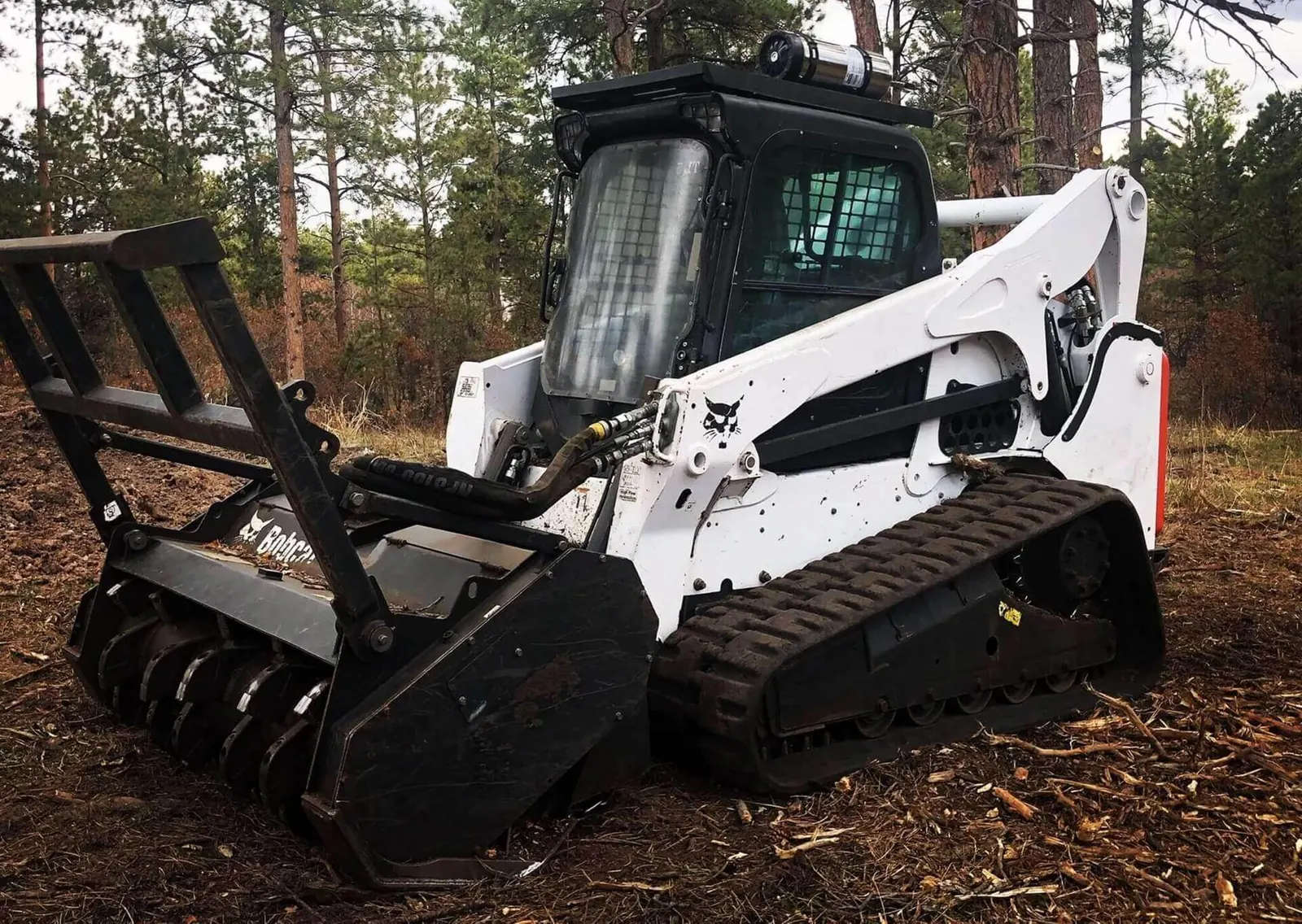 Track loader with a forestry mulching head on fresh mulch in a wooded lot